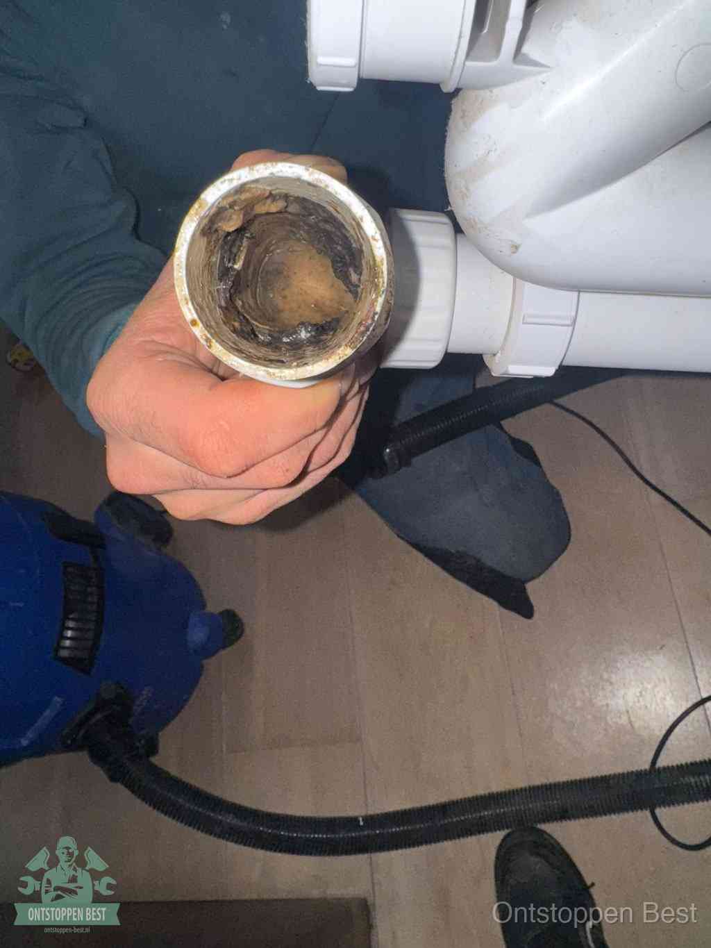 Een losgekoppeld PVC-afvoerbuisstuk dat van binnen volledig is dichtgeslibd met vet en vuil, de meest voorkomende oorzaak van verstoppingen in Best