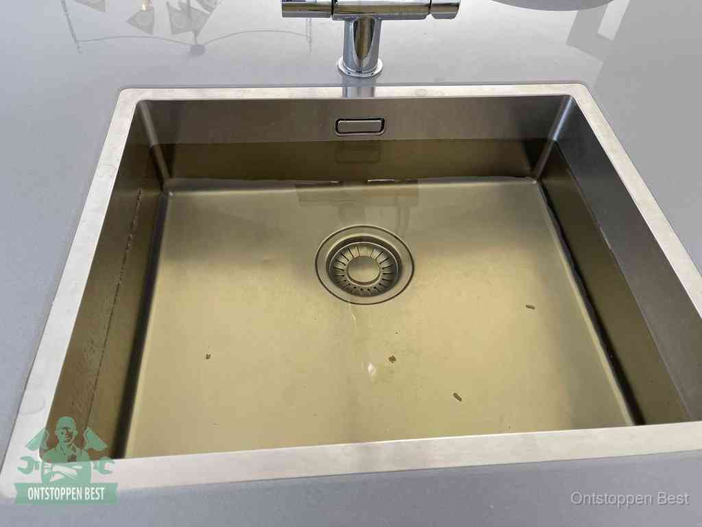 Een RVS spoelbak met stilstaand water dat niet wegloopt, een van de eerste signalen van een beginnende verstopping in Best