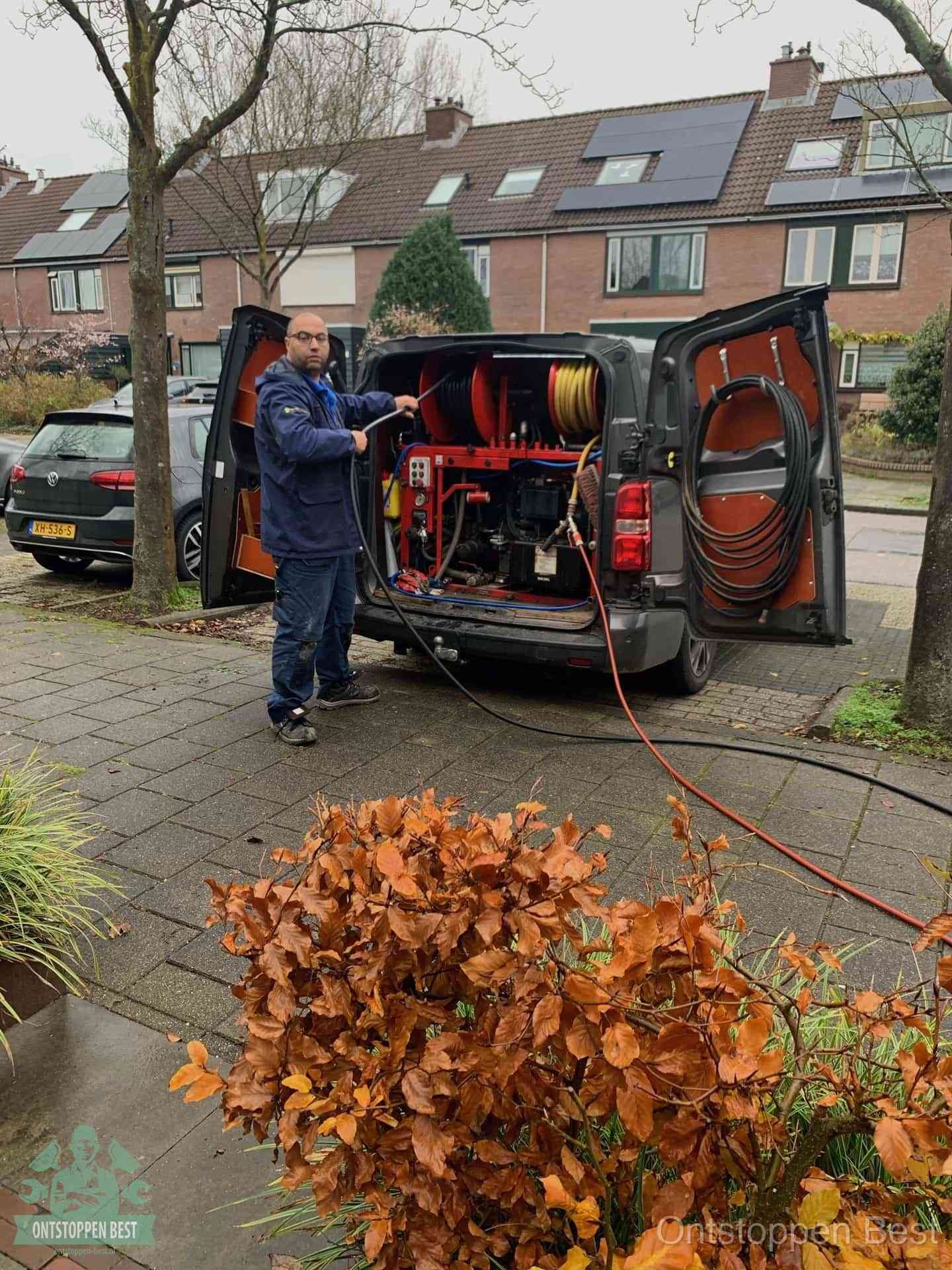 Een monteur staat bij zijn open bestelbus met hogedruk-rioolreinigingsapparatuur, klaar om binnen 30 minuten uit te rukken voor een spoedverstopping in Best