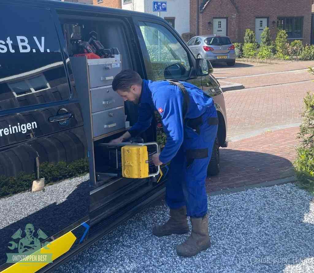 Een monteur pakt gereedschap uit de bedrijfsbus, het moment om een professionele ontstoppingsdienst in te schakelen in Best