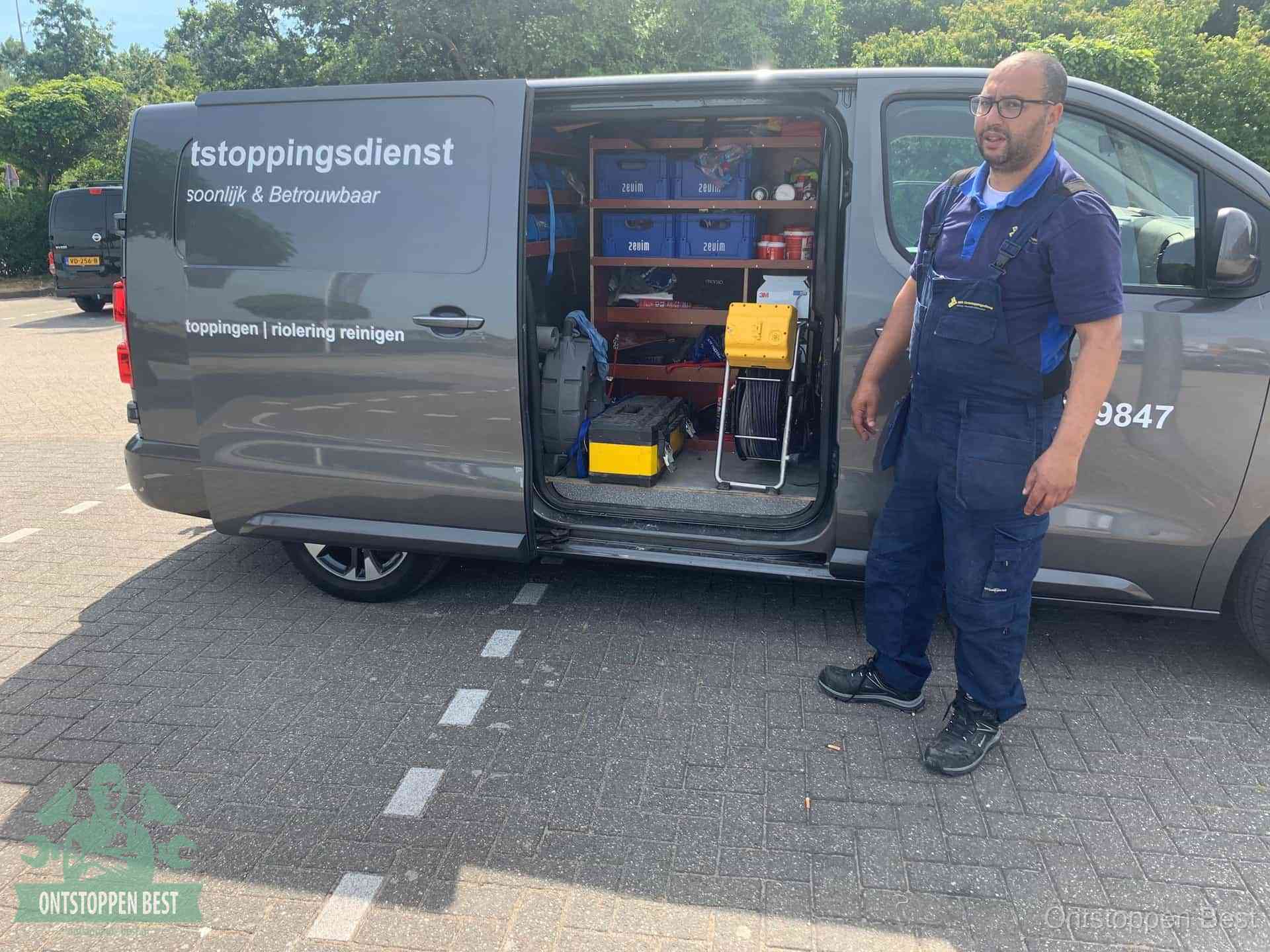 Een monteur staat klaar bij zijn bedrijfsbus met gereedschap, de vaste werkwijze van de ontstoppingsdienst in Best